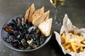 Boiled mussels in copper cooking dish on dark wooden background close up