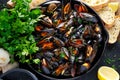 Boiled mussels in iron pan cooking dish. with herbs, butter, lime, parsley, garlic and fresh bread.