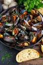 Boiled mussels in iron pan cooking dish. with herbs, butter, lime, parsley, garlic and fresh bread. Royalty Free Stock Photo