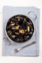 Boiled mussels in a metal bowl and fork on a light blue cloth