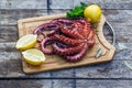 Boiled octopus ready for serve with lemon and parsley on wooden board