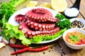 Boiled octopus tentacles, Octopus food on wooden cutting board background, cooked squid salad chili sauce seafood cuttlefish