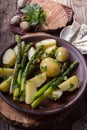 Boiled potato with grilled green asparagus on brown plate over on old wooden background. Overhead. Rustic style