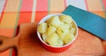 Boiled potatoes with herbs in a red plate on a wooden stand, close-up, proper nutrition