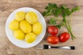 Boiled potatoes in plate, parsley, tomatoes and fork on table Royalty Free Stock Photo