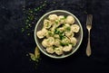 Boiled prepared homemade russian pelmeni, dumplings, ravioli with meat on grey plate with fresh parsley, pepper, black