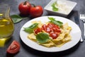 Boiled ravioli with basil, cheese and tomato sauce on a black background