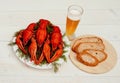 Boiled red crawfish on a white plate with green fennel on a white wooden background.