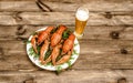 Boiled red crawfish on a white plate with green fennel on a wooden background.