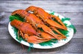 Boiled red crawfish on a white plate with green fennel on a wooden background.