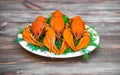 Boiled red crawfish on a white plate with green fennel on a wooden background.