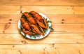 Boiled red crawfish on a white plate with green fennel on a wooden background.