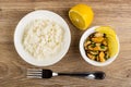 Rice in plate, half of lemon, mussels with parsley in bowl, fork on table. Top view Royalty Free Stock Photo