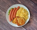 Boiled sausages, scrambled eggs and bread toasts with egg on a wooden table Royalty Free Stock Photo