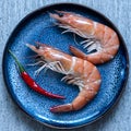 Boiled shrimp with red hot chilli pepper on a blue plate background, close-up Royalty Free Stock Photo