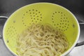 Boiled tagliatelle pasta straining in a colander