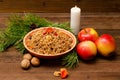 Boiled wheat - a traditional Christmas treat of the Slavs on Christmas Eve kutia. Fur-tree branch, apple, candle on a wooden backg Royalty Free Stock Photo