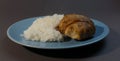 Boiled white rice with chicken cutlet wrapped in bacon on a gray background blue plate