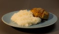 Boiled white rice with chicken cutlet wrapped in bacon on a gray background blue plate