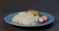 Boiled white rice with fish cutlet wrapped in bacon on a gray background blue plate. Baked fish meatball with garnish of rice and