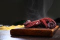 Boiled whole octopus on a wooden cutting board. Whole octopus carcass. Cooking seafood dishes. Dark background. Protein food. Side