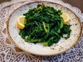 Boiled wild cooked greens close up top view, served with lemon and olive oil on a dish