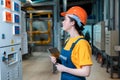 Boiler room. Portrait of a young female worker in helmet and uniform with a tablet in her hand. Side view. The concept of Royalty Free Stock Photo