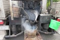 Boiling hot asphalt is filled into a bucket from an asphalt machine to fill a pothole. Road construction, road rehabilitation, as