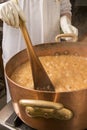 Boiling syrup of sugar in copper pan with thermometer and big spoon. Brown colour because of evaporation. Royalty Free Stock Photo