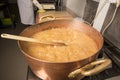 Boiling syrup of sugar in copper pan with thermometer and big spoon. Brown colour because of evaporation. Royalty Free Stock Photo