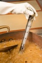 Boiling syrup of sugar in copper pan with thermometer and big spoon. Brown colour because of evaporation. Royalty Free Stock Photo