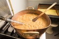 Boiling syrup of sugar in copper pan with thermometer and big spoon. Brown colour because of evaporation. Royalty Free Stock Photo