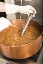 Boiling syrup of sugar in copper pan with thermometer and big spoon. Brown colour because of evaporation. Royalty Free Stock Photo