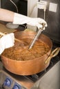 Boiling syrup of sugar in copper pan with thermometer and big spoon. Brown colour because of evaporation. Royalty Free Stock Photo