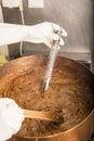 Boiling syrup of sugar in copper pan with thermometer and big spoon. Brown colour because of evaporation. Royalty Free Stock Photo