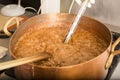 Boiling syrup of sugar in copper pan with thermometer and big spoon. Brown colour because of evaporation. Royalty Free Stock Photo