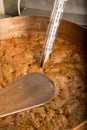 Boiling syrup of sugar in copper pan with thermometer and big spoon. Brown colour because of evaporation. Royalty Free Stock Photo