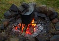 Boiling water in kettle on fire surrounded by stones