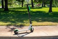 A Lime brand dockless electronic scooter sits on a sidewalk, unattended. These app-based scooters