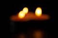 Bokeh composition of three candles on dark luxury night background. Blur black table, side view. Candles Burning at Night. Orange