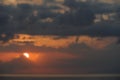 Bokeh effect of the ocean and sky at the sunset with dark clouds and partially hidden sun