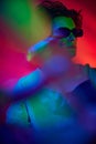 Bokeh effect. Portrait of handsome young man in stylish sunglasses posing over red background in neon light Royalty Free Stock Photo