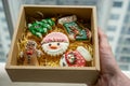 Bokeh Photo of Person holding a Paper Gift Box with Christmas Gingerbread Cookies in Different Christmas Theme Designs