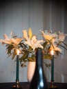 Table set with wine bottle and candle lit white lilies. Copy space Royalty Free Stock Photo