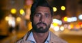 Bokeh shot of handsome indian man looking at camera in city at night Royalty Free Stock Photo