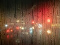 Raindrops on a bus window with blurred headlights behind