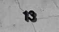 Number thirteen in bold black against a textured wall, perfect for eerie Halloween designs and mysterious projects Royalty Free Stock Photo