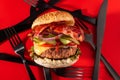 Bold fresh cheeseburger loaded with lettuce, cucumber, tomato and bacon on vibrant red