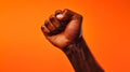 Clenched fist against bright orange backdrop symbolizing strength