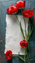 Bold red tulips frame a piece of crinkled white paper against a dark blue textured backdrop, ideal for invitations or